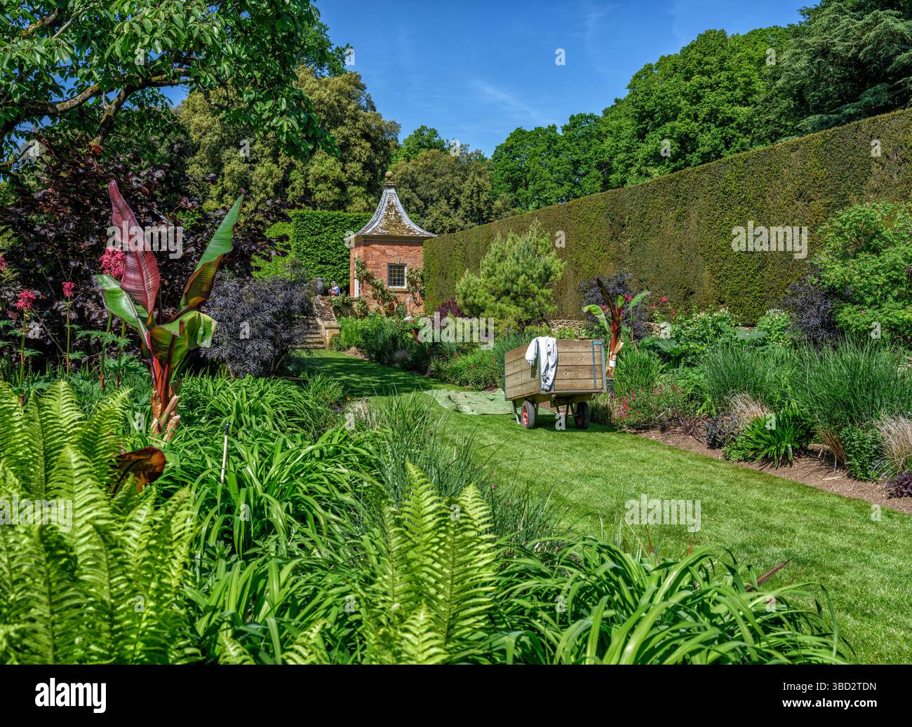 Gartenkarre, Summerhouse und Perennial Grenzen an Hidcote Manor Gardens, einem der großen englischen Gärten in den Cotswold Hills von Wiltshire, Großbritannien Stockfoto