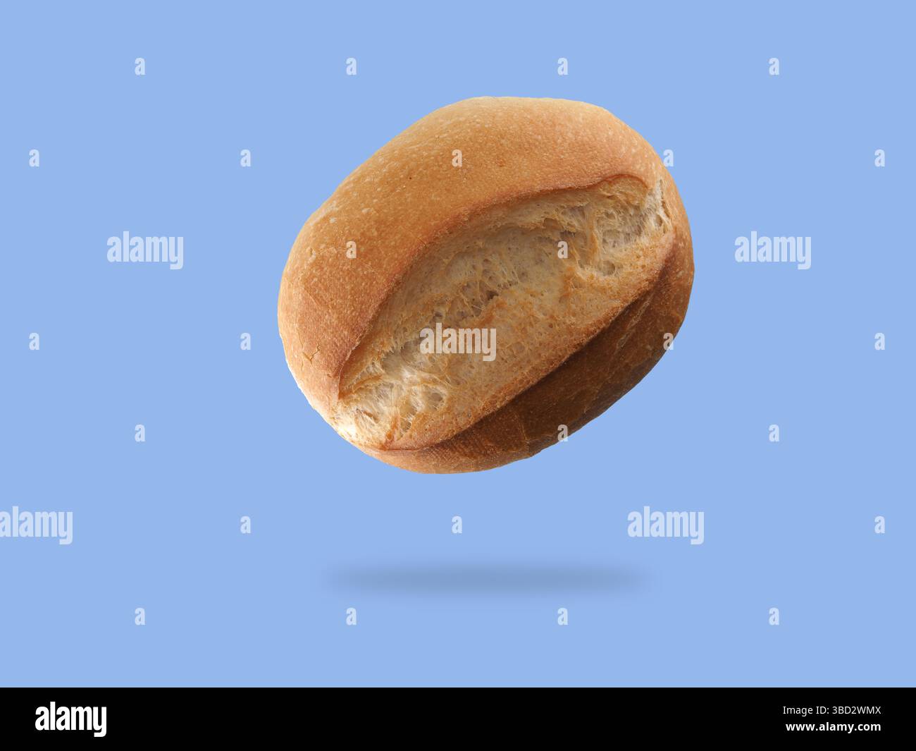 Ein Brötchen schwebt in der Luft vor einem schlichten blauen Hintergrund, das sein weiches Interieur und die goldbraune Kruste unterstreicht und die frisch gebackene App unterstreicht Stockfoto