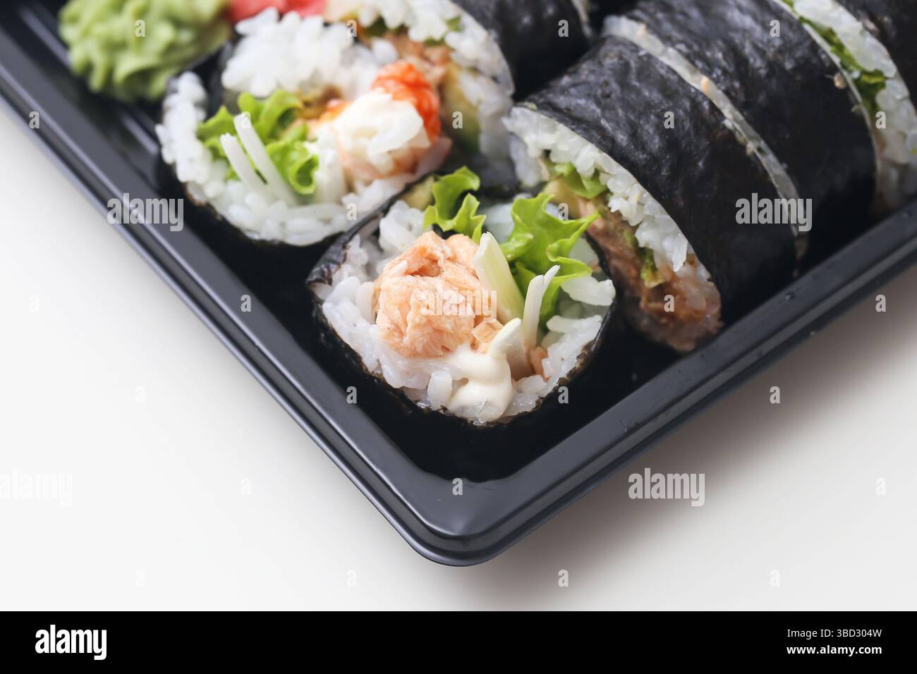 Frische Sushi-Brötchen aus der Nähe. Gemischtes Maki mit Thunfisch, Salat, Reis und Algen. Japanisches Essen in schwarzem Tablett. Leckerer Snack mit Meeresfrüchten. Gesunde Gourmet-Mahlzeit. Stockfoto