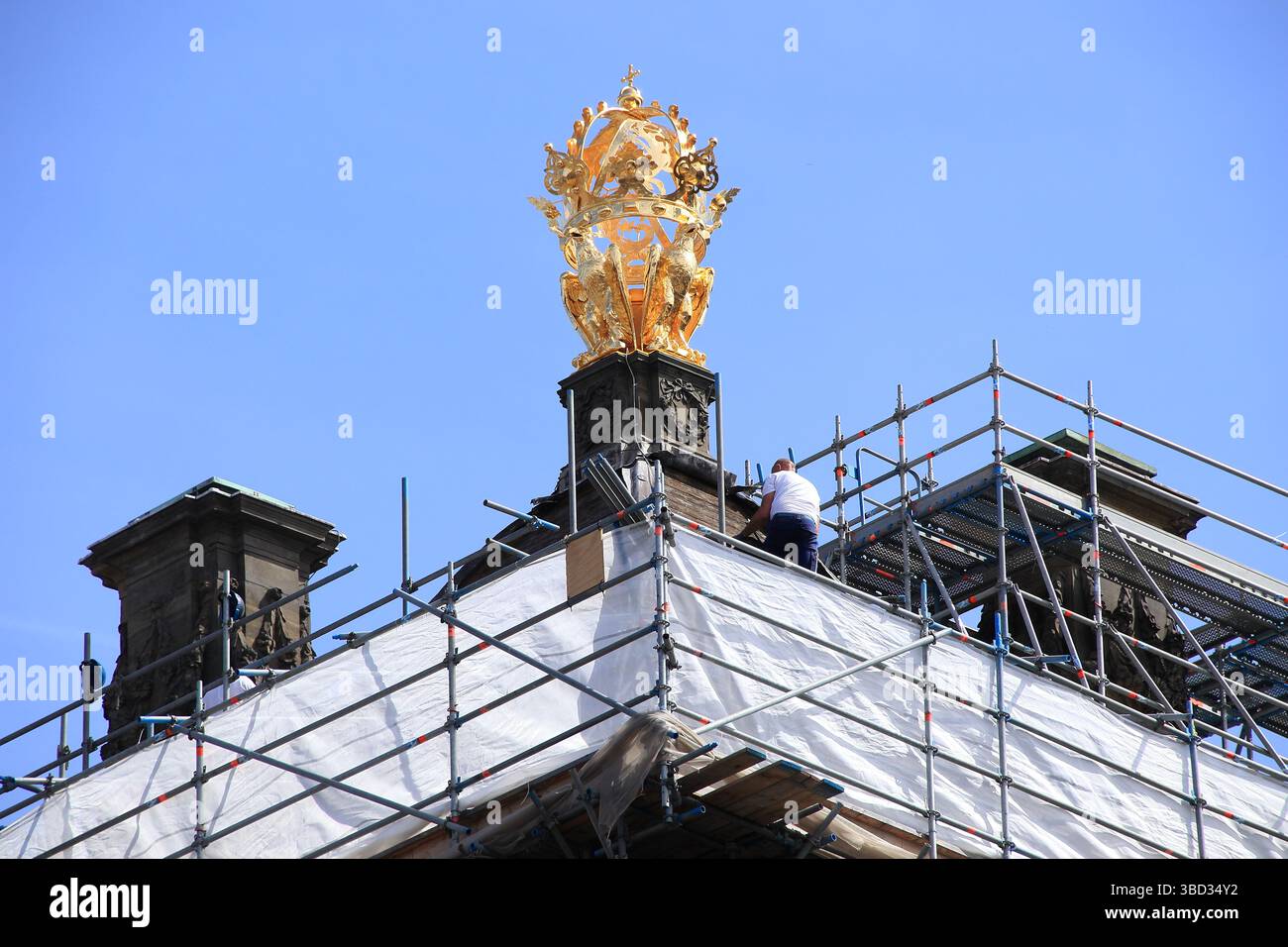 Goldene Dekoration mit Adlern und Gerüsten mit einem Mann auf dem Dach des Königspalastes in Amsterdam, Niederlande, Mai 2025. Stockfoto