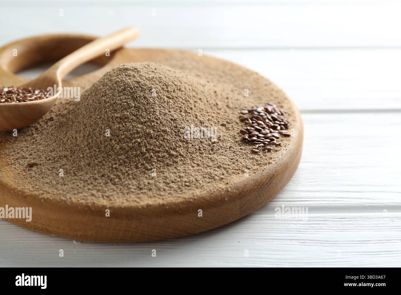 Leinsamenmehl und Löffel mit Samen auf weißem Holztisch, Nahaufnahme Stockfoto