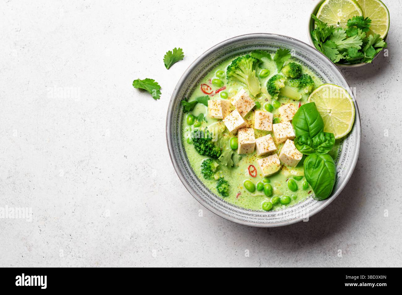 Thailändische grüne vegane Curry-Suppe mit Tofu auf weißem Hintergrund, Draufsicht, Kopierraum. Gesunde vegane Mahlzeit, thailändische Küche, asiatisches Mittagessen. Stockfoto