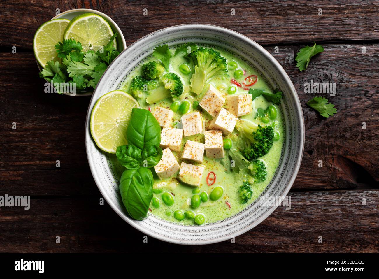 Thailändische grüne vegane Curry-Suppe mit Tofu auf dunklem hölzernem Hintergrund, Blick von oben. Gesunde vegane Mahlzeit, thailändische Küche, asiatisches Mittagessen. Stockfoto