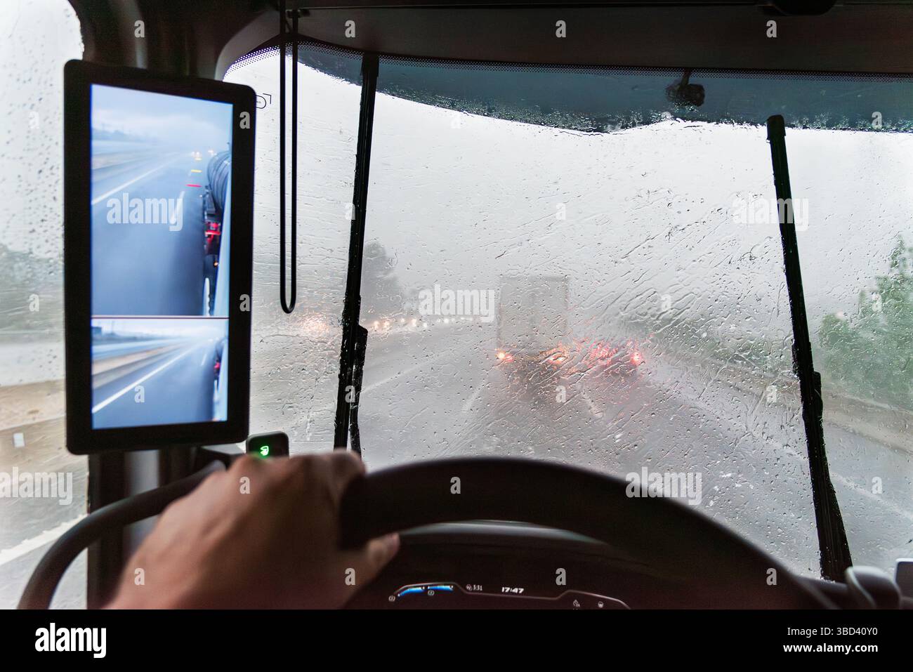 Innenansicht des Lkw mit Windschutzscheibe, die von starkem Regen bedeckt ist, die Sicht auf die Straße verringert und die Scheibenwischer kämpfen gegen den Sturm. Stockfoto