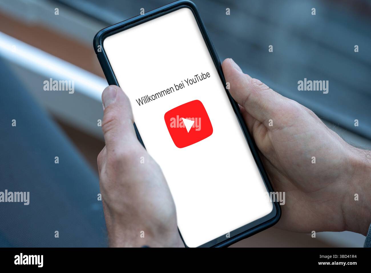 Bayern, Deutschland - 22. Mai 2025: FOTOMONTAGE, Startbildschirm der YouTube-App auf einem Smartphone - das rote Wiedergabesymbol erscheint zusammen mit dem Willkommenstext Willkommen bei YouTube. *** FOTOMONTAGE, Startbildschirm der YouTube-App auf einem Smartphone das rote Wiedergabe-Symbol erscheint zusammen mit dem Begrüßungstext Willkommen bei YouTube. Stockfoto
