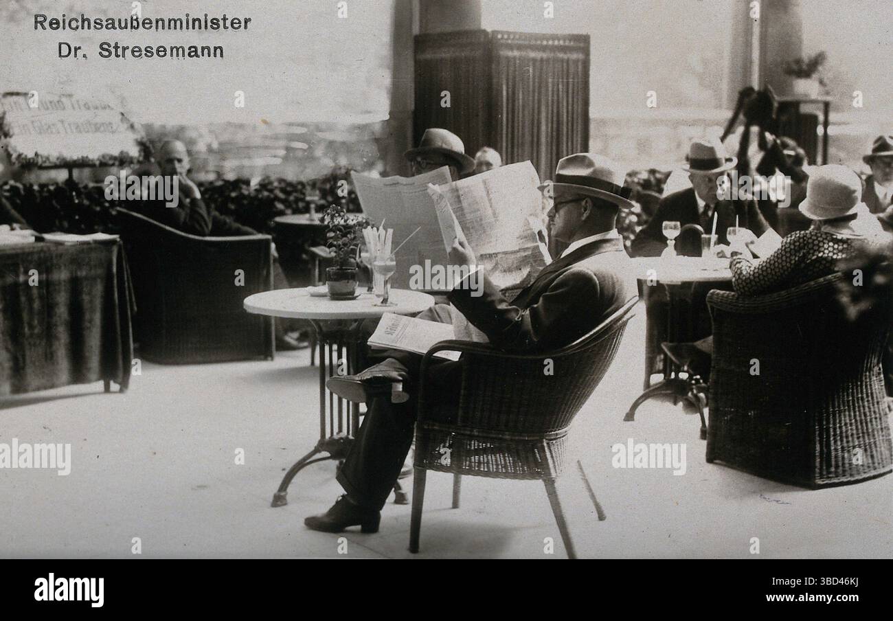 Der Weimarer Bundeskanzler und Außenminister Gustav Stresemann liest eine Zeitung auf einer Café-Terrasse. Gustav Ernst Stresemann (ˈɡʊstaf ˈʃtʁeːzəˌman ⓘ; 10. Mai 1878 – 3. Oktober 1929) war ein deutscher Staatsmann in der Weimarer Republik, der von August bis November 1923 als Bundeskanzler und von 1923 bis 1929 als Außenminister tätig war. Seine bemerkenswerteste Leistung war die Aussöhnung zwischen Deutschland und Frankreich, für die er und die französische Premierministerin Aristide Briand 1926 den Friedensnobelpreis erhielt. Stockfoto