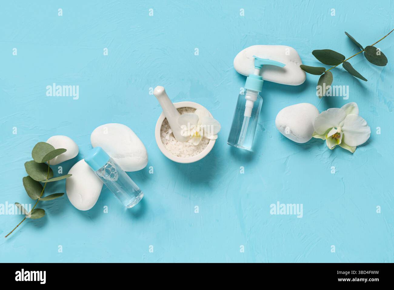 Komposition mit Kosmetikprodukten, Kursteinen und Eukalyptuszweigen auf farbigem Hintergrund Stockfoto