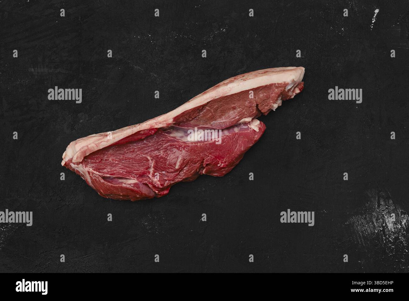 Blick von oben auf rohes Rindfleisch Ribeye Lippe auf mit Haut Auf schwarzem Hintergrund Stockfoto
