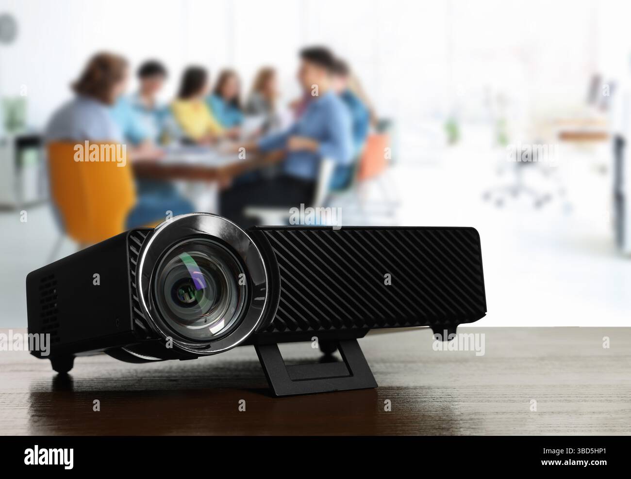 Moderner Videoprojektor auf Holztisch und Personen, die im Konferenzraum arbeiten, selektiver Fokus Stockfoto