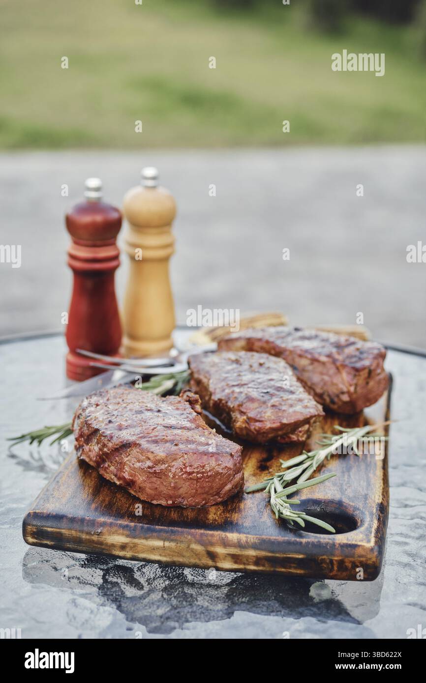 Gegrillte New York Strip Steaks auf dem Glastisch im Hinterhof Stockfoto