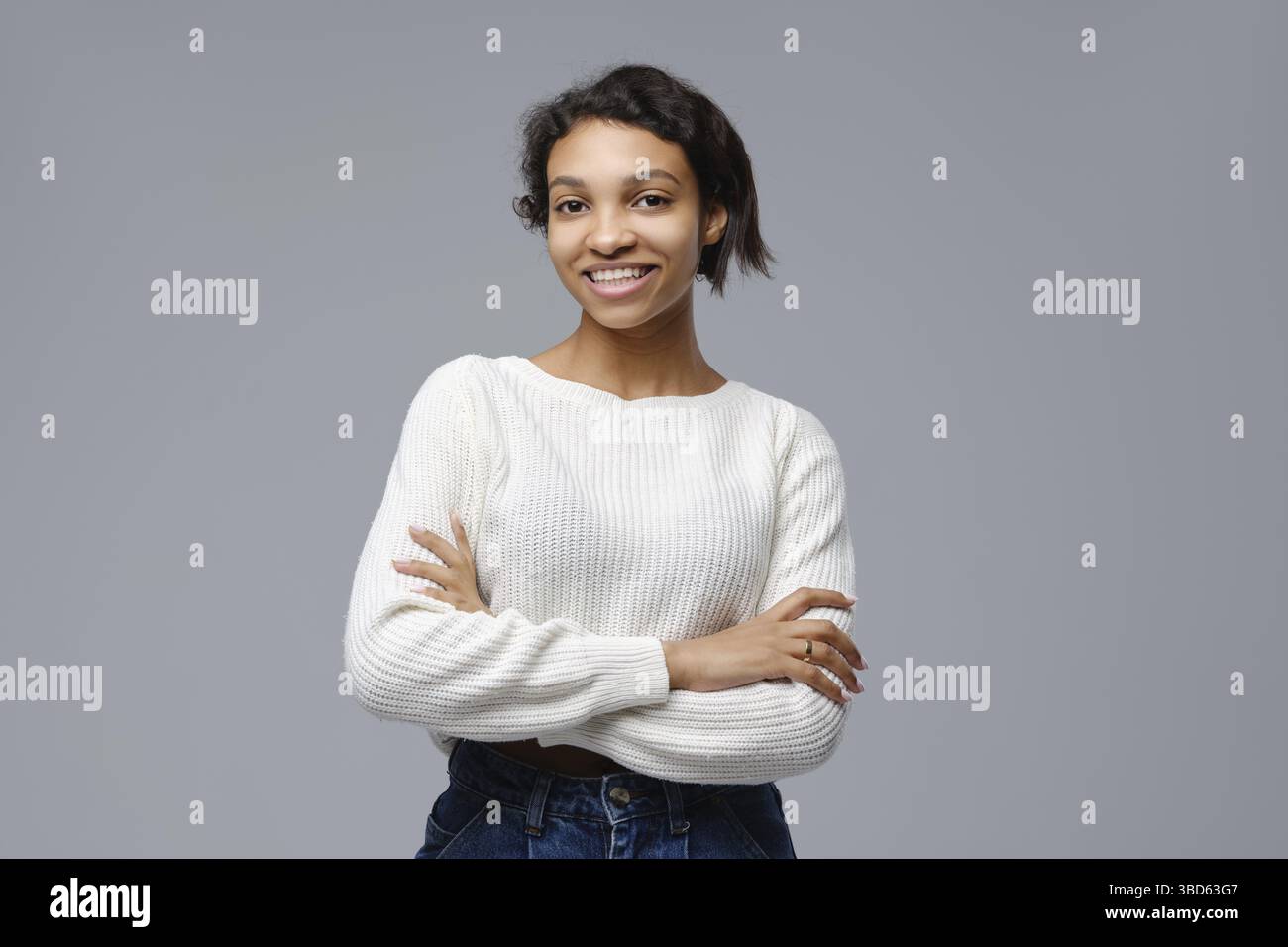 Porträt einer schönen glücklichen schwarzen Frau, die mit gekreuzten Armen steht Stockfoto