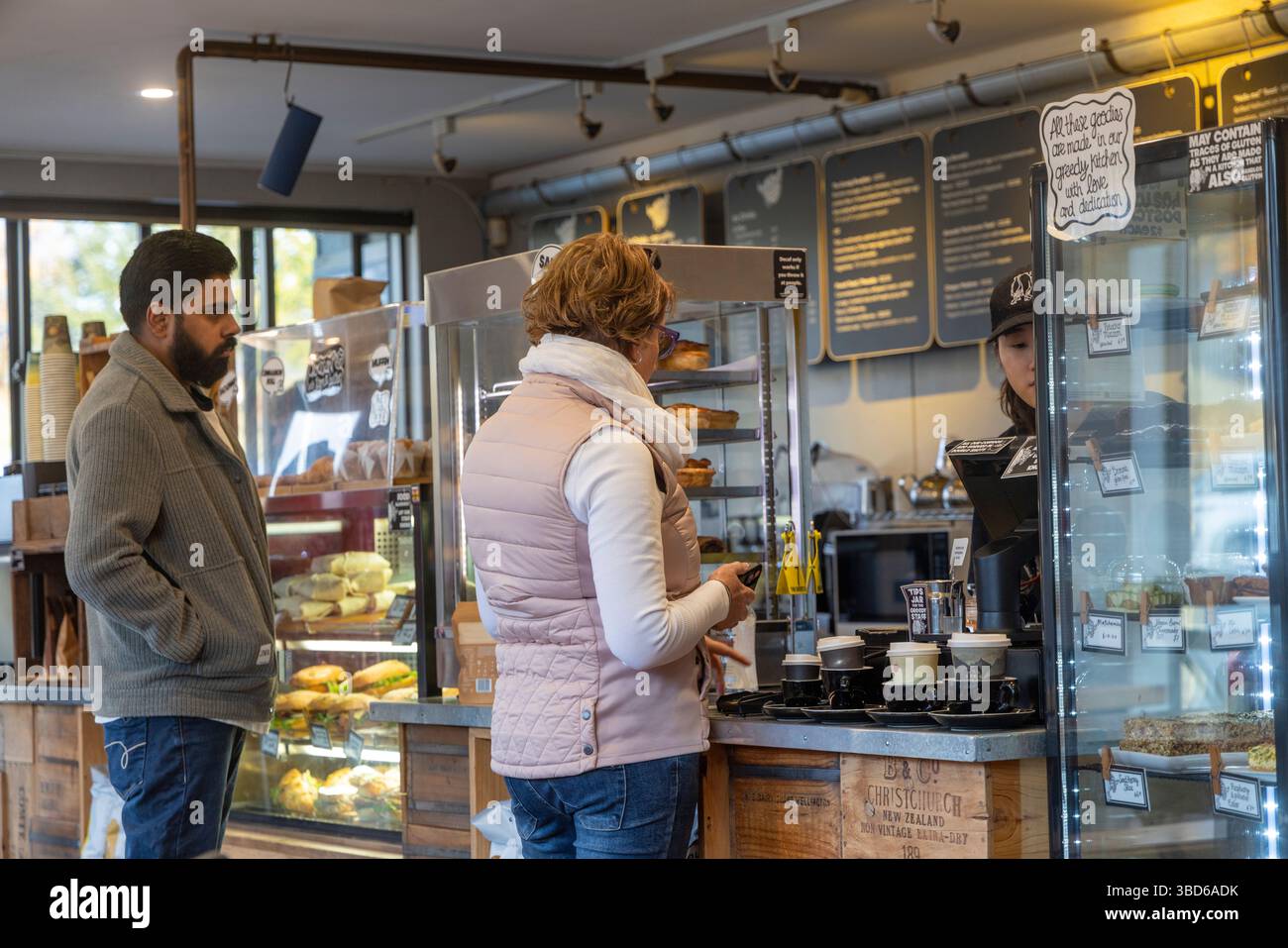 Lake Tekapo Township, Canterbury, Südinsel, Neuseeland, Model freigelassen Frau bestellt Kaffee und Frühstück an der Theke Stockfoto