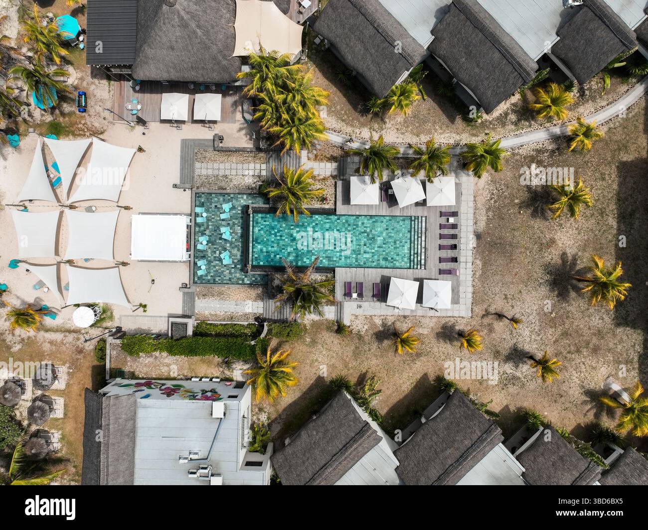 Blick von oben auf den rechteckigen Pool, Sonnenschirme und Strandmöbel in einem Boutique-Hotel auf Mauritius Stockfoto