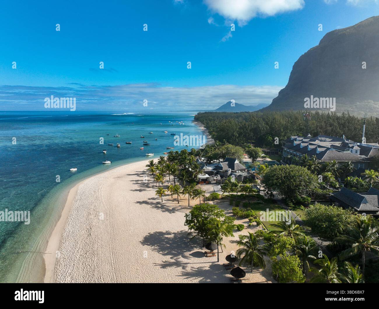 Drohnenaufnahme von Sandstrand gesäumt mit Sonnenschirmen und tropischem Resort Stockfoto