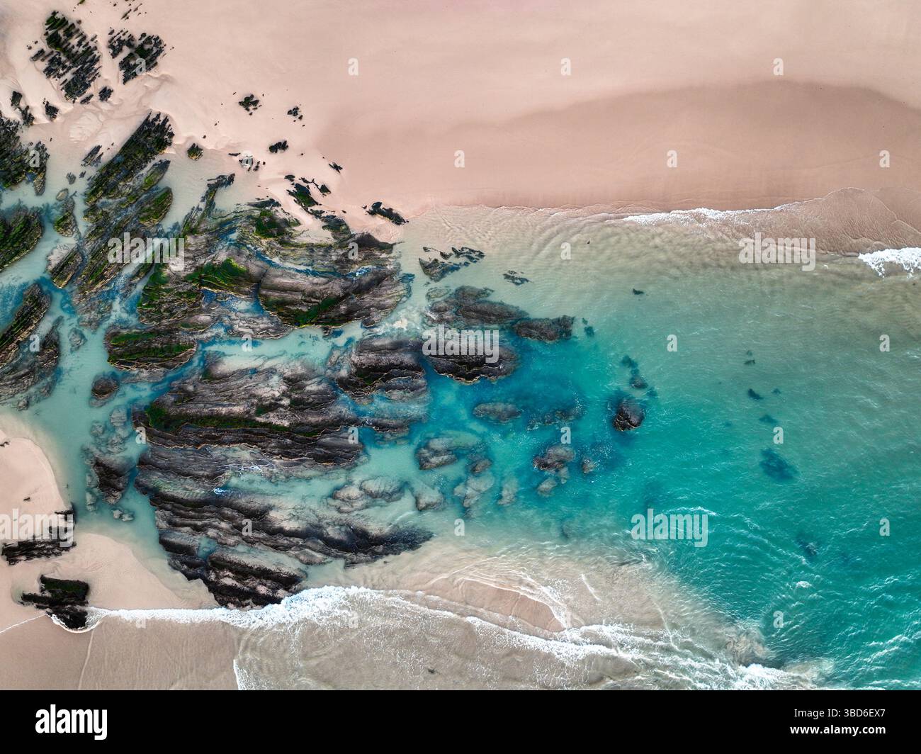 Luftbild von der felsigen Küste und dem flachen türkisfarbenen Meer in der Nähe des Sandstrandes Stockfoto