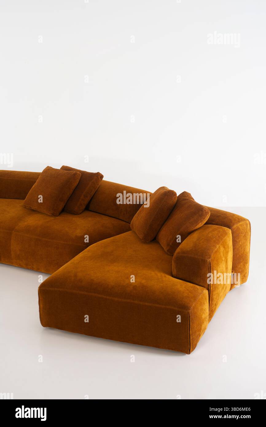Ein braunes Sofabett mit passenden Kissen steht vor einem hellen weißen Hintergrund. Das modulare Design unterstreicht seinen modernen Stil Stockfoto