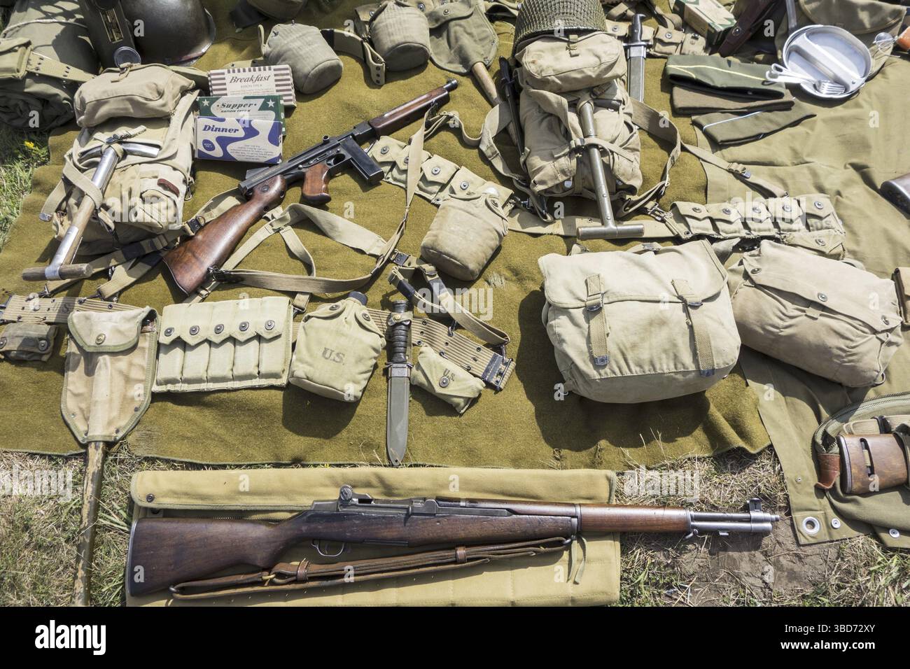 WW2 US-Soldat Outfit und Waffen auf dem Boden im Zweiten Weltkrieg militaria Messe zeigen M1 Garand Gewehr und Thompson Maschinenpistole angezeigt Stockfoto