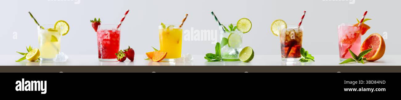 Sammlung erfrischender Getränke mit Eis in einem Glasbecher, dekoriert mit Scheiben und Strohhalmen mit Zutaten und Blättern um hellen isolierten Hintergrund. Stockfoto