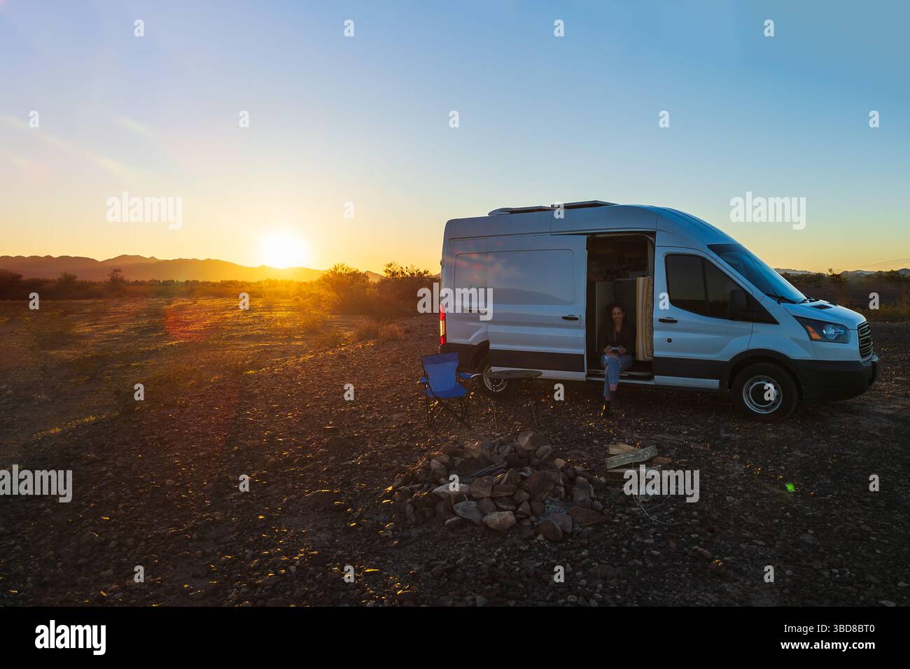 Frau sitzt im Wohnwagen bei Sonnenuntergang auf Quartzsite BLM Land, Arizona Stockfoto