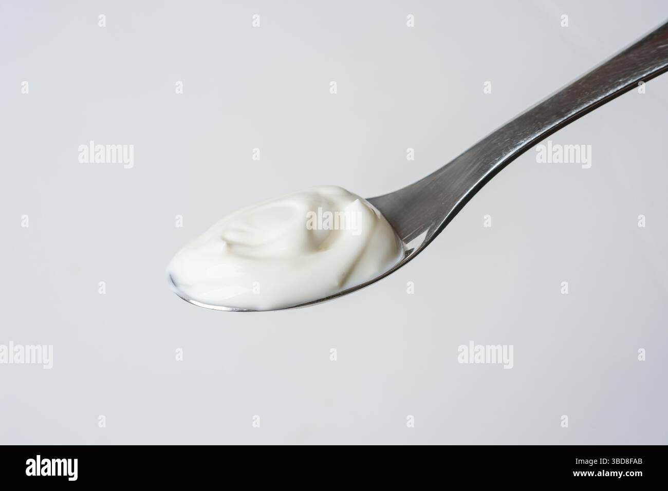Löffel cremiger Joghurt auf weißem Hintergrund, minimalistischer Stil Stockfoto