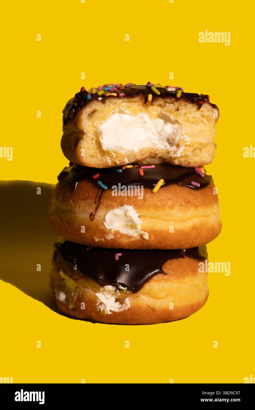 Drei Boston Cream Donuts auf gelbem Hintergrund Stockfoto