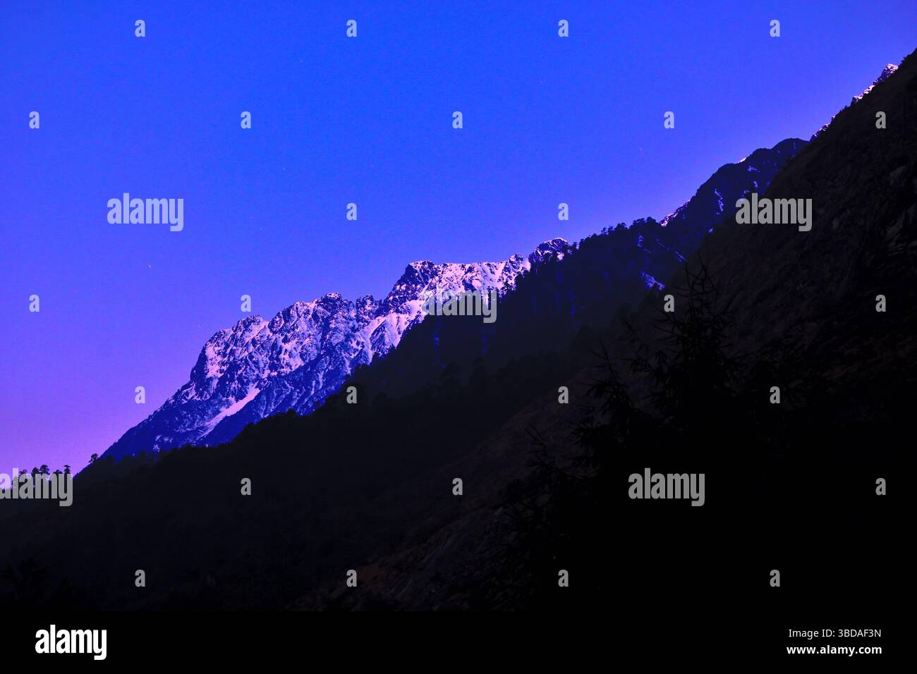 Sonnenaufgang über einer Reihe von Berggipfeln im Lachung Valley, Sikkim während der März Winter Stockfoto