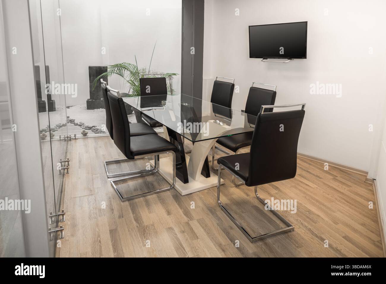 Ein moderner Tagungsraum mit transparentem Glastisch, umgeben von eleganten schwarzen Stühlen, schafft eine stilvolle und professionelle Umgebung für Diskus Stockfoto