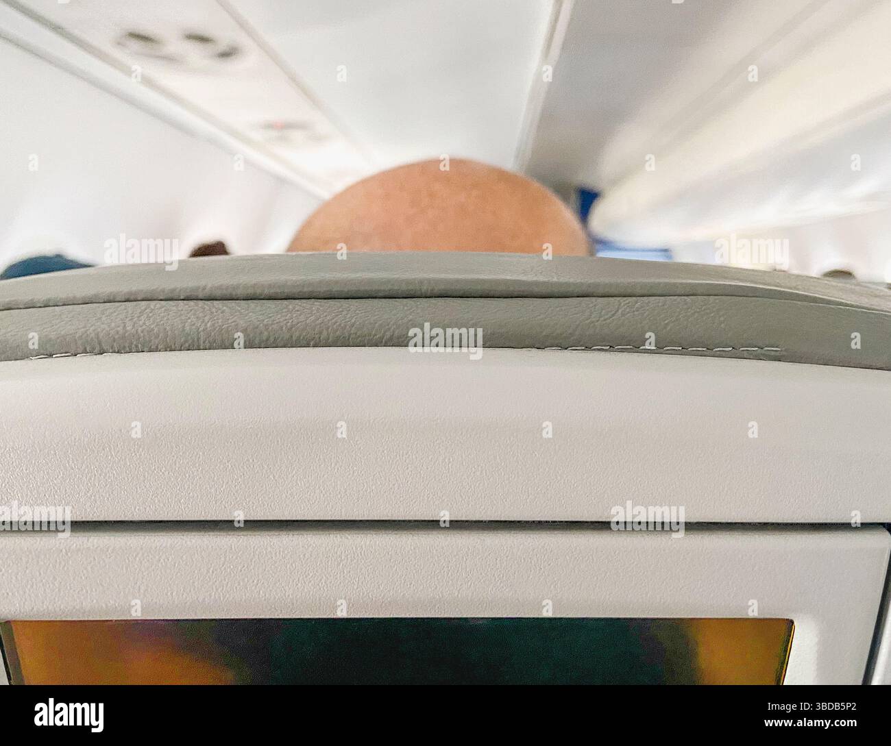 Oben auf dem Glatzkopf des Mannes im Flugzeugsitz, Rückansicht Stockfoto