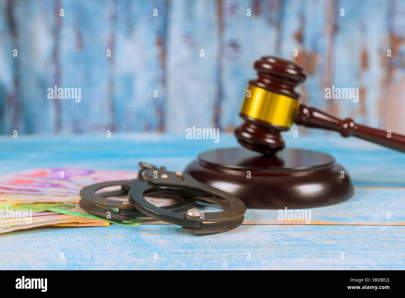 Hammer, Handschellen, Geld auf hölzernem Boden im Gerichtssaal ernsthafte Stimmung reflektiert juristische Themen rechtliche Konsequenzen. Stockfoto