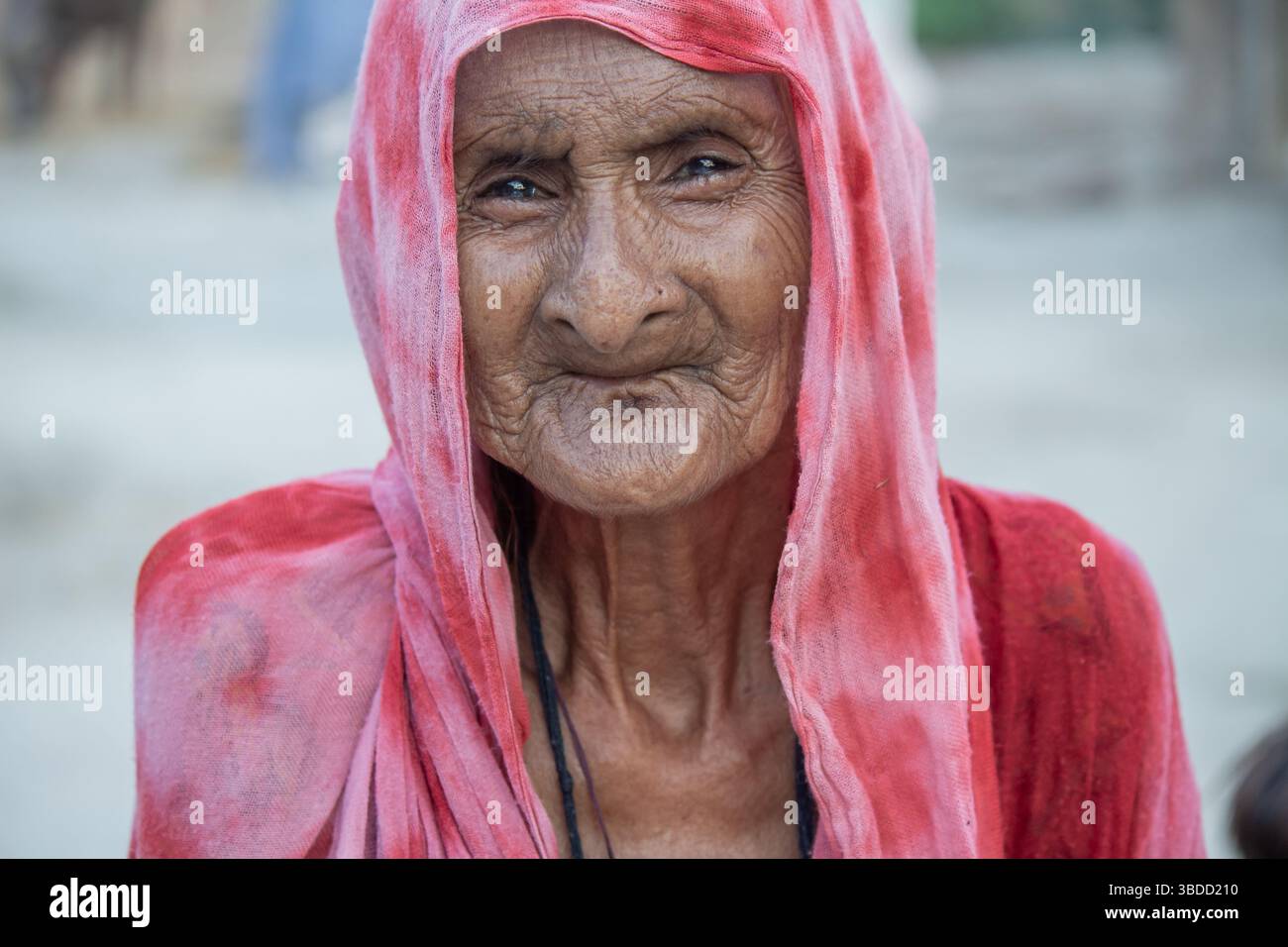 Porträt einer älteren Frau in einem roten traditionellen Schal, lächelnd mit Grace in einer ländlichen Umgebung Stockfoto