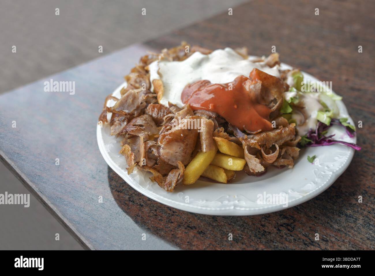 Döner-Dönerteller mit Fleisch, Pommes frites, Salat und zwei Saucen in einem türkischen Fast-Food-Restaurant in Deutschland, Kopierraum, ausgewählter Fokus, sehr Stockfoto