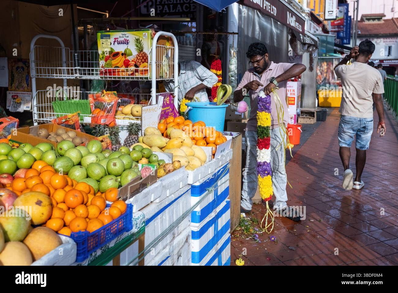 Straßenszene auf dem Obstmarkt in Little India in Singapur der südindianer webt die Blumengirlande für den Tempel Stockfoto
