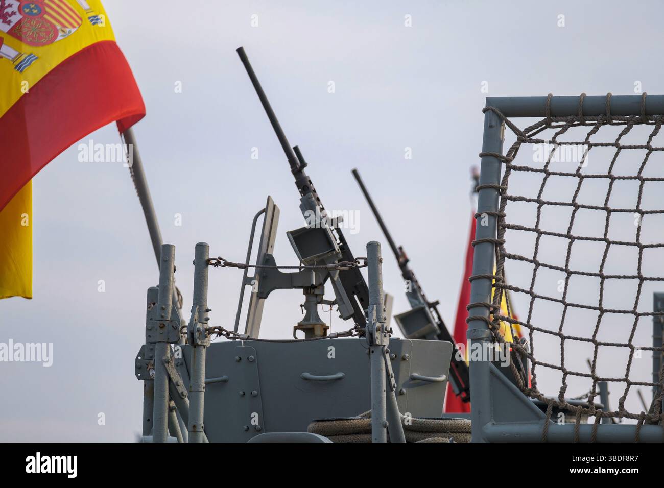 Spanisches Militärschiff mit schweren Maschinengewehren, Sicherheitsbarrieren und sichtbarer spanischer Flagge, die den Kontext der maritimen Verteidigung darstellt Stockfoto