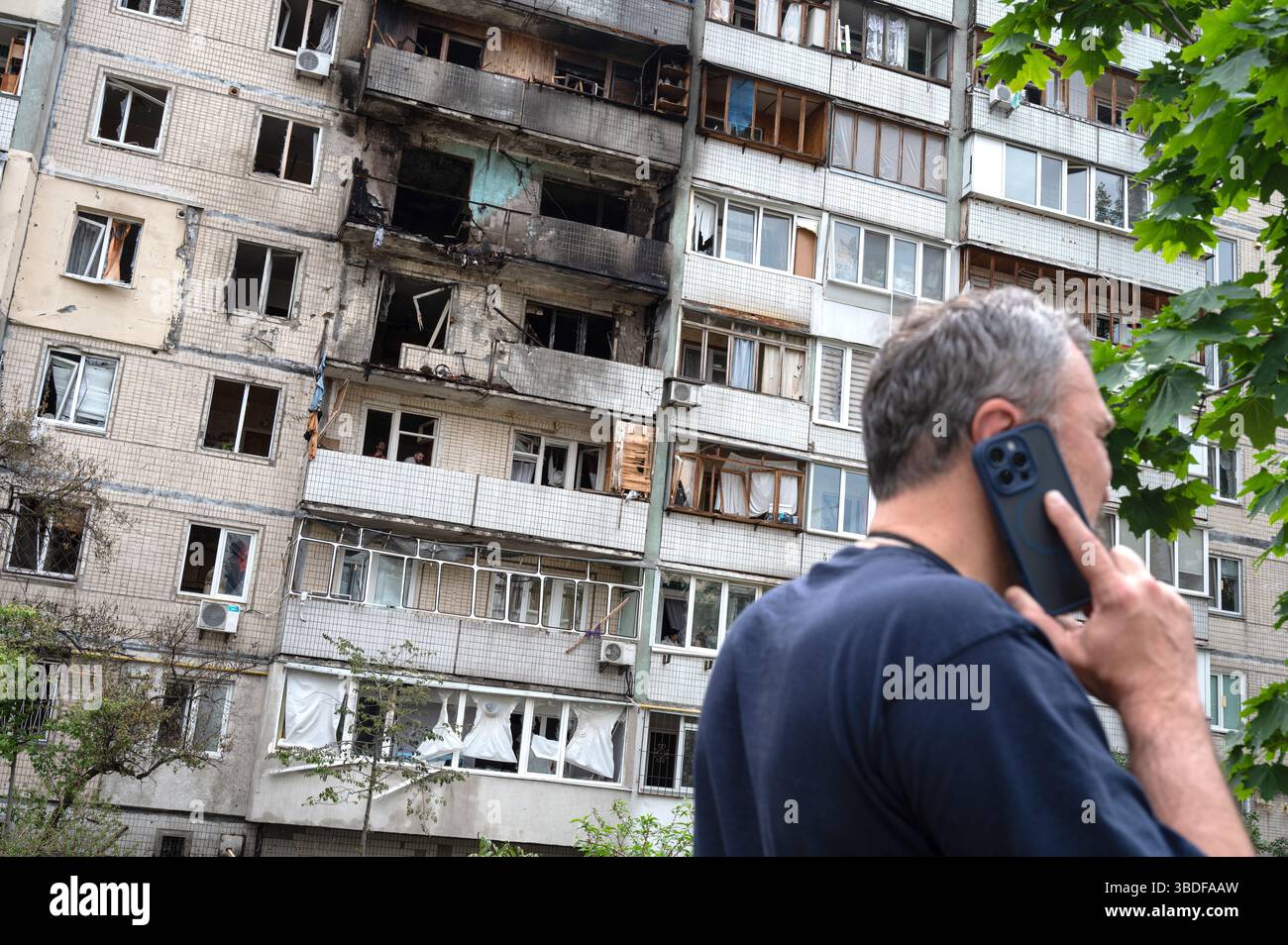 Kiew, Ukraine. Mai 2025. Ein Mann spricht auf dem Handy vor einem Wohnblock im Bezirk Obolonskyi, der durch den Angriff von Trümmern während des russischen Raketen- und Drohnenangriffs am 24. Mai 2025 in Kiew, Ukraine, beschädigt wurde. Kiew und sieben andere Regionen der Ukraine wurden von Russland in großem Maßstab angegriffen, bei dem 250 Schlagdrohnen und 14 ballistische Raketen beteiligt waren. (Foto: Danylo Antoniuk/Ukrinform) Credit: Ukrinform/Alamy Live News Stockfoto
