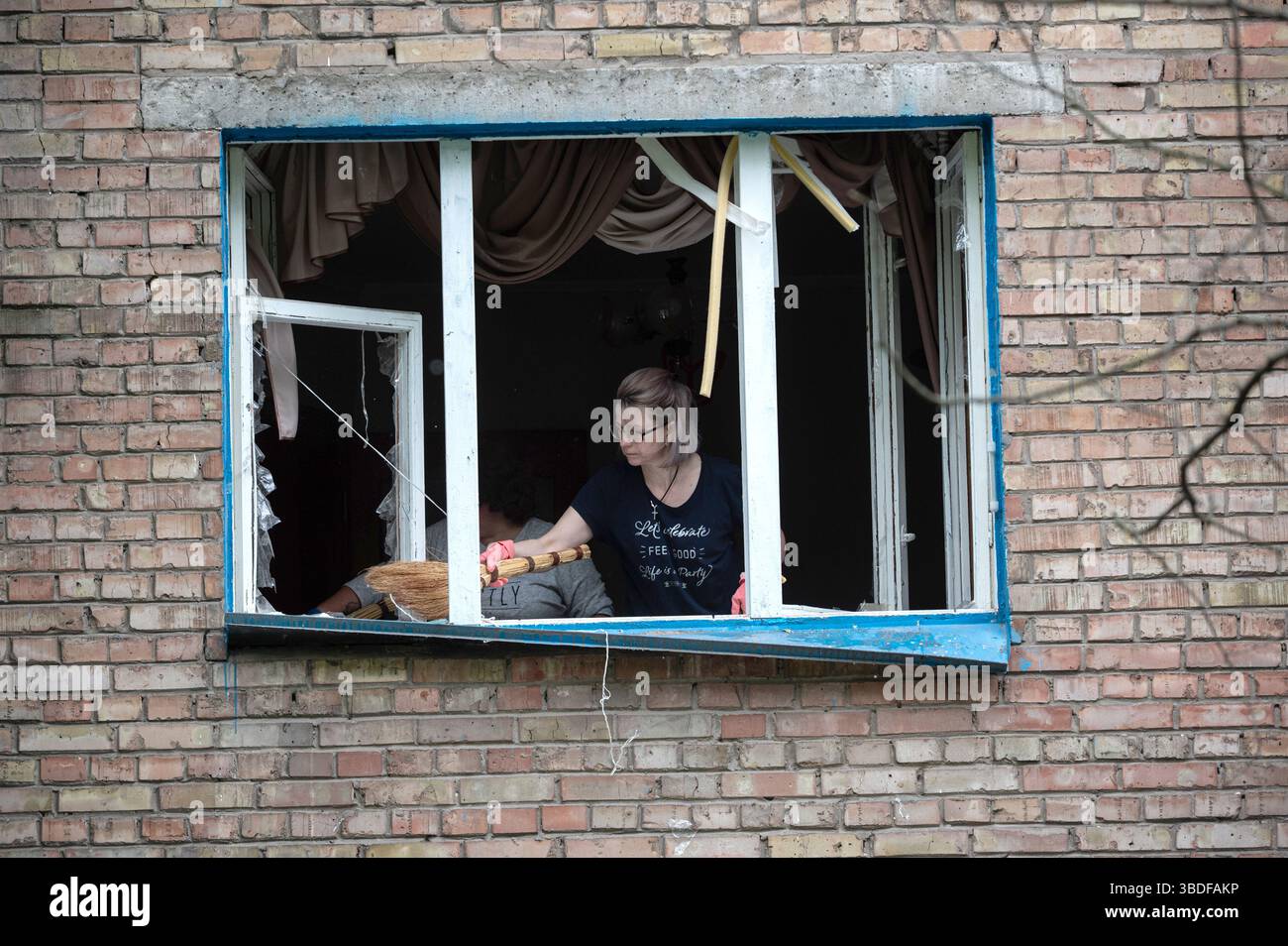 Kiew, Ukraine. Mai 2025. Frauen fegen Glasscherben von der Fensterbank eines zertrümmerten Fensters in einem Wohnblock im Bezirk Solomianskyi weg, der durch den russischen Raketen- und Drohnenangriff am 24. Mai 2025 in Kiew, Ukraine, beschädigt wurde. Kiew und sieben andere Regionen der Ukraine wurden von einem russischen Großangriff mit 250 Schlagdrohnen und 14 ballistischen Raketen angegriffen. (Foto: Danylo Antoniuk/Ukrinform) Credit: Ukrinform/Alamy Live News Stockfoto