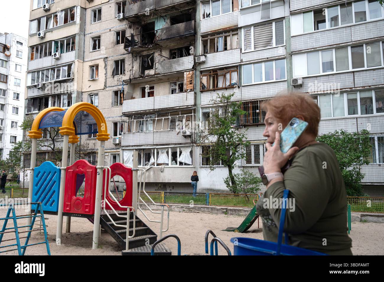 Kiew, Ukraine. Mai 2025. Eine Frau spricht auf dem Handy vor einem Wohnblock im Bezirk Obolonskyi, der durch den Angriff von Trümmern während des russischen Raketen- und Drohnenangriffs am 24. Mai 2025 in Kiew, Ukraine, beschädigt wurde. Kiew und sieben andere Regionen der Ukraine wurden von einem russischen Großangriff mit 250 Schlagdrohnen und 14 ballistischen Raketen angegriffen. (Foto: Danylo Antoniuk/Ukrinform) Credit: Ukrinform/Alamy Live News Stockfoto