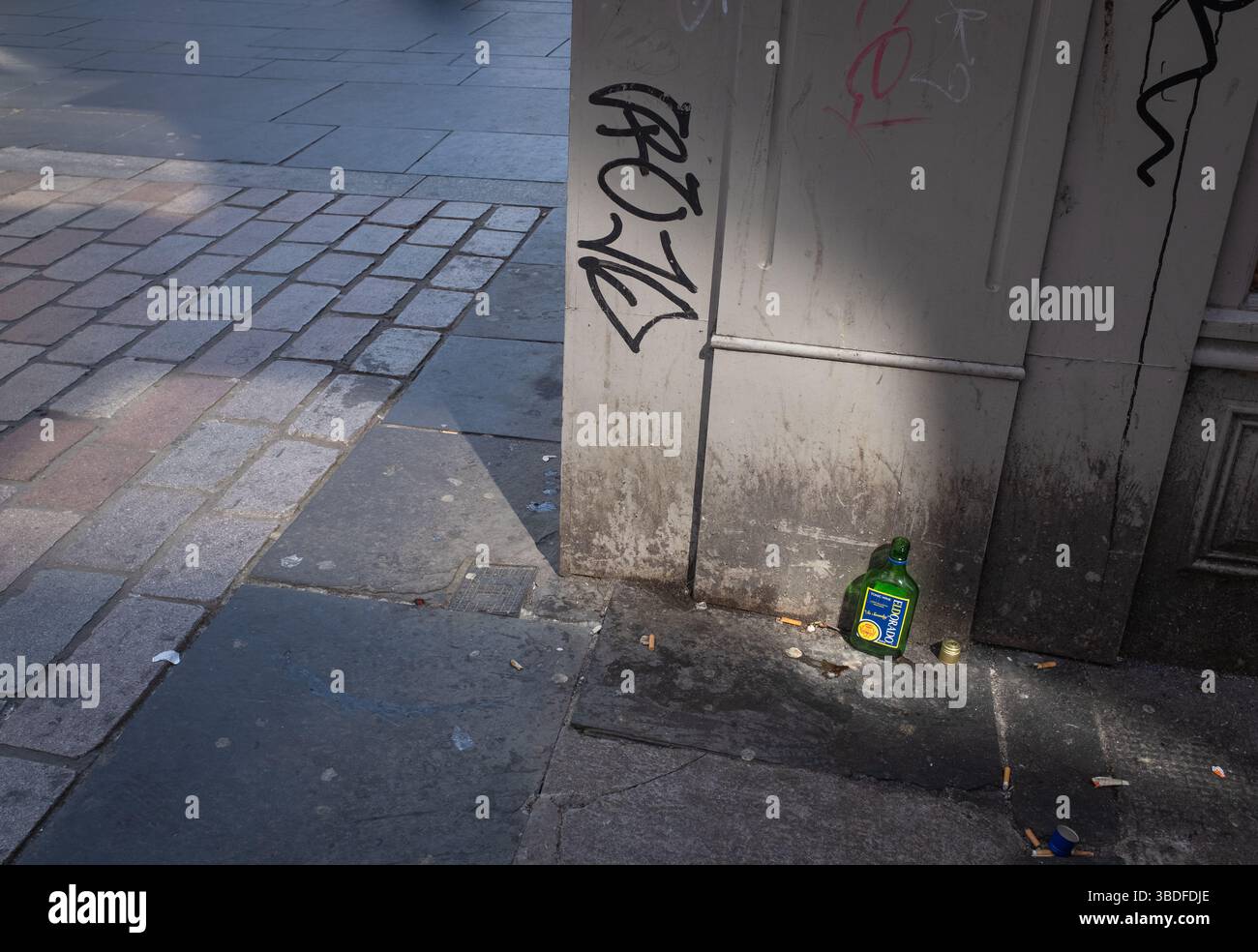 Eine Flasche Eldorado Tonic Wine liegt verlassen in der Gordon Street im Stadtzentrum von Glasgow, Schottland. Graffiti und Zigarettenkippen in der Nähe. Stockfoto