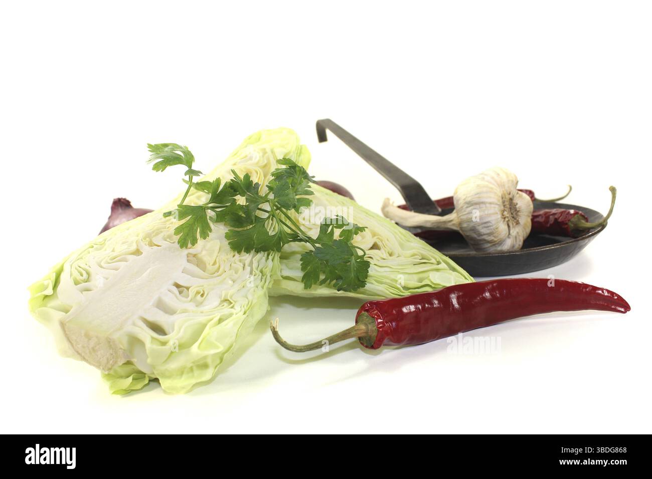 Spitzkohl mit Petersilie und Pfanne vor hellem Hintergrund Stockfoto