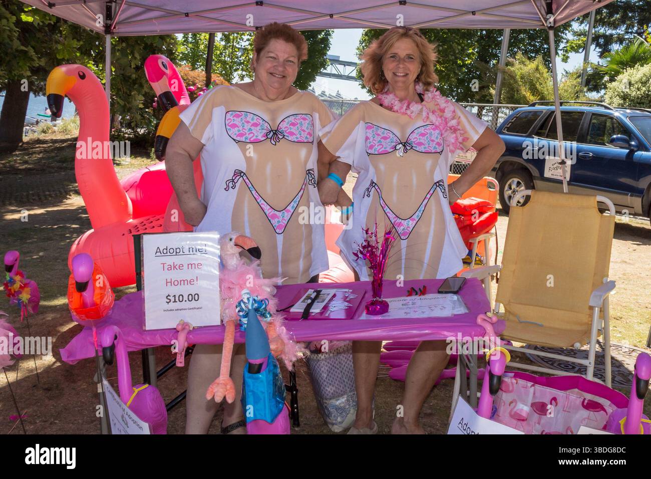 The Big Float, Portland, Oregon – 14. Juli 2018: Zwei Frauen in Bikinishirts verkaufen Flamingoadoptionen für 10 US-Dollar, um die Veranstaltung zu unterstützen. Stockfoto
