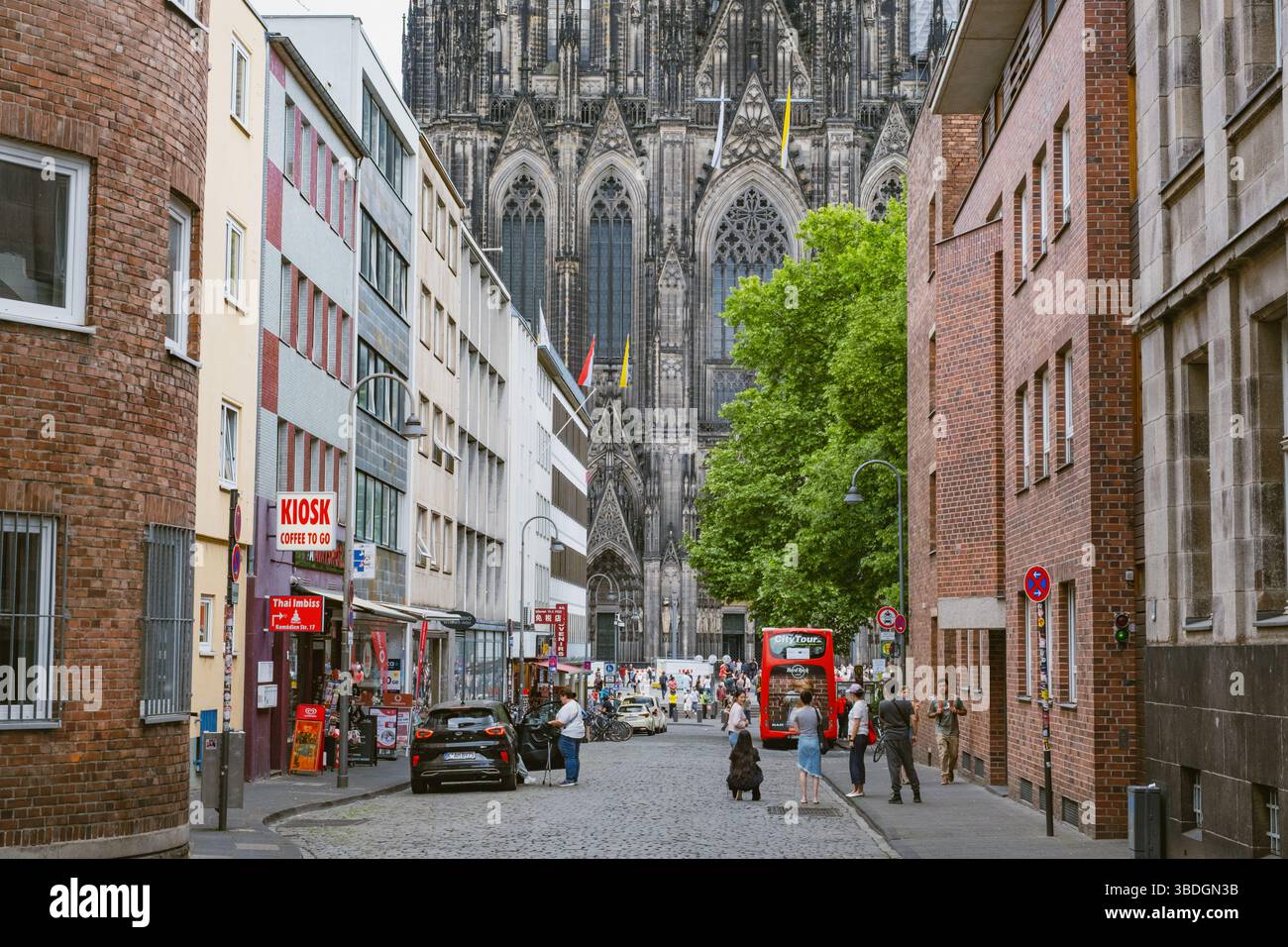 Kleine Straße im Stadtzentrum mit dem berühmten Kölner Domgebäude im Hintergrund Stockfoto