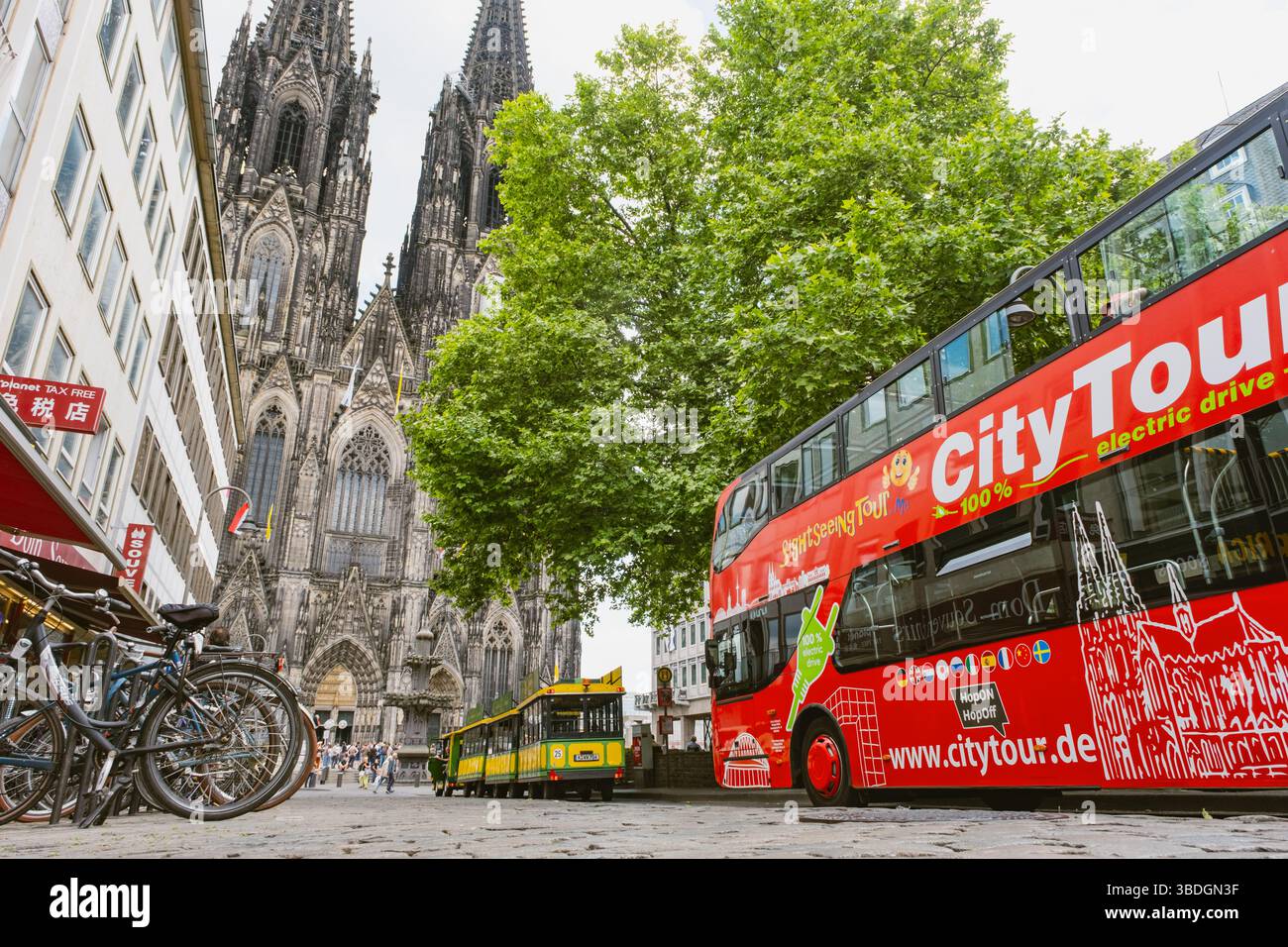 Kölner Dom mit Tourbussen und Fahrrädern in einer belebten Straße Stockfoto