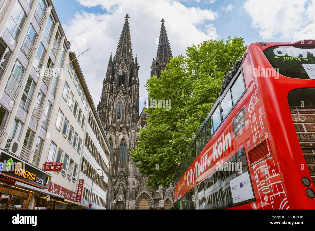 Kölner Dom mit Tourbussen und Fahrrädern in einer belebten Straße Stockfoto