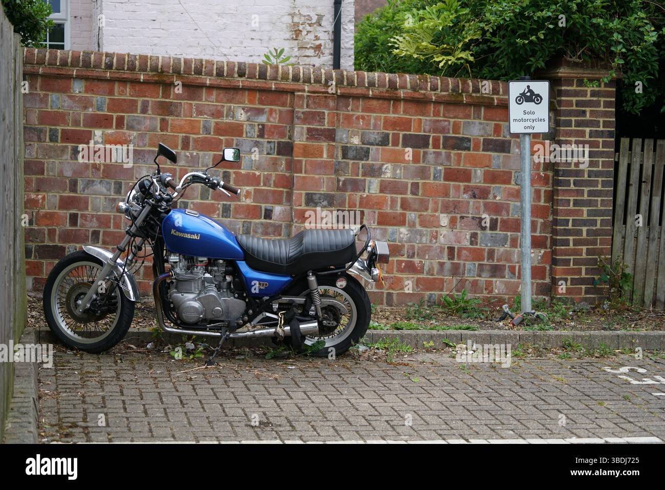 Blaues Kawasaki-Motorrad in der Nähe der Ziegelmauer mit entsprechendem Schild. Dorking, Großbritannien Stockfoto