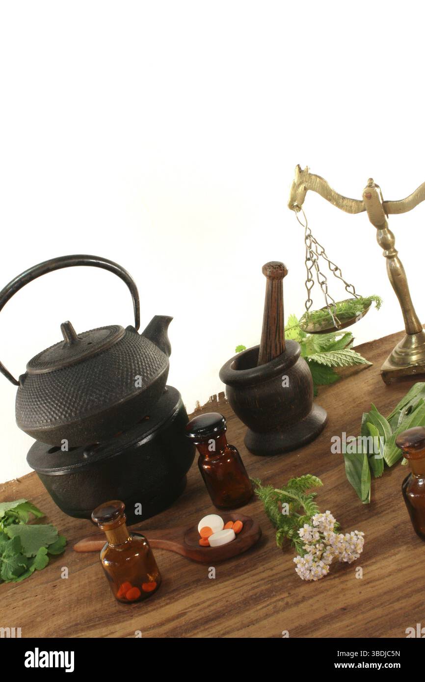 Apothekenwaage mit Mörtel, Wasserkocher, Apothekerflasche und frischen Kräutern Stockfoto