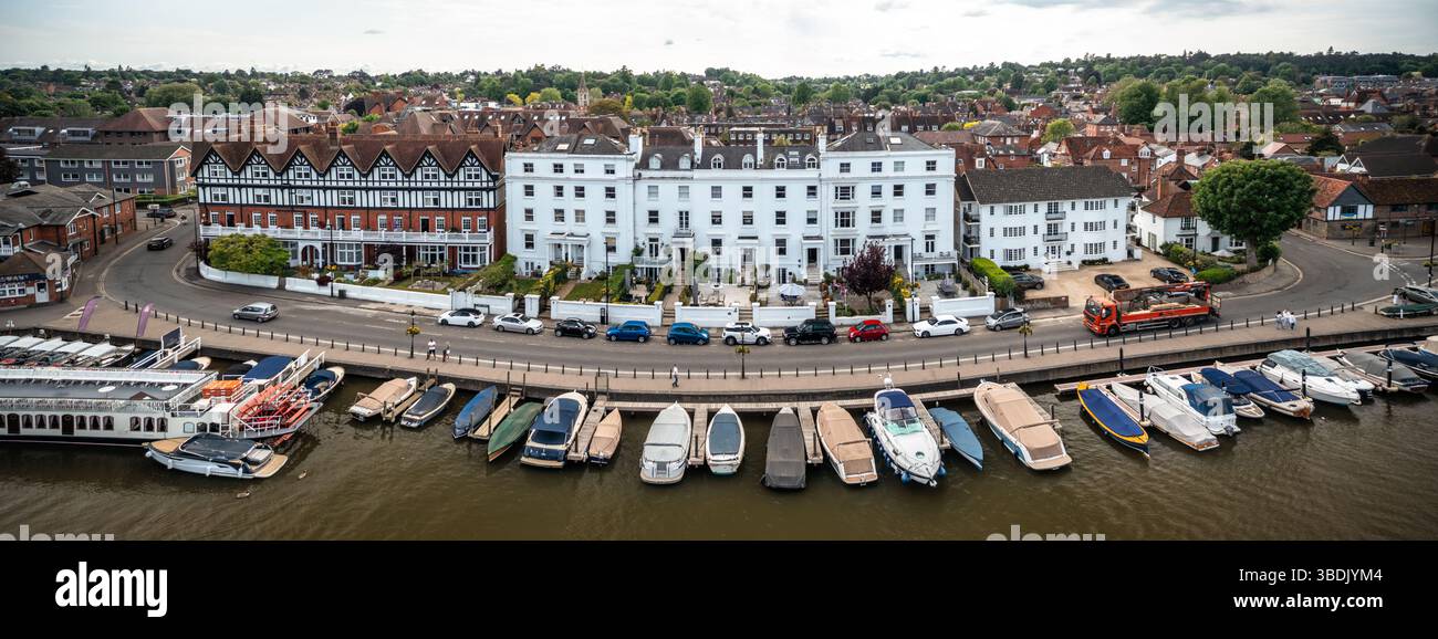 Aus der Vogelperspektive sehen Sie elegante Terrassengebäude aus weißem und rotem Backstein, die eine gekrümmte Flussstraße säumen, mit zahlreichen kleinen Booten, die entlang der ri ankern Stockfoto