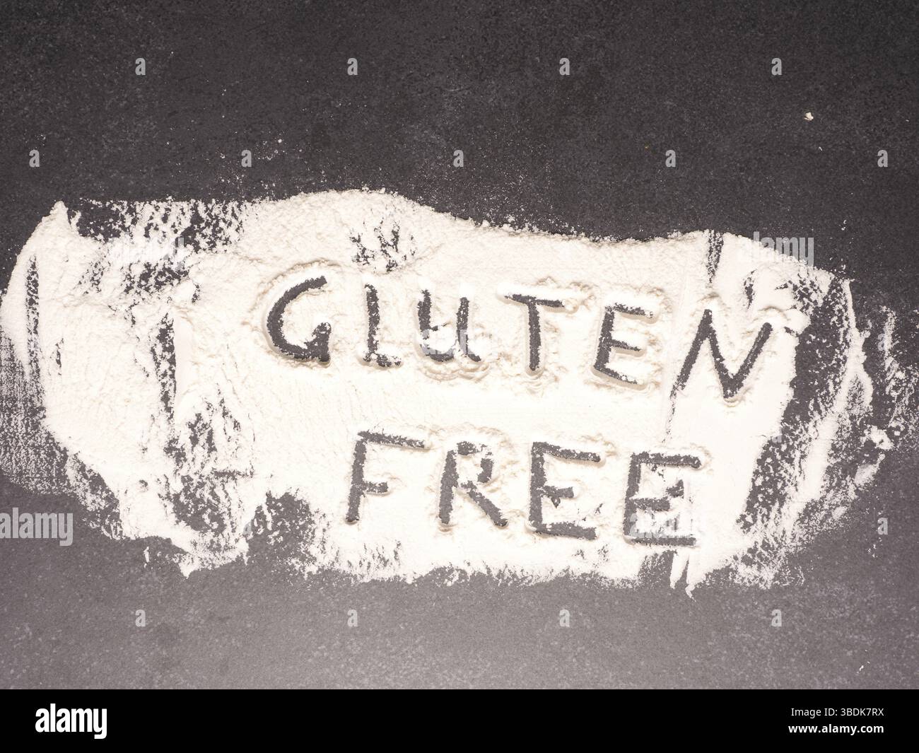 Glutenfrei in Mehl auf einem dunklen Stein Küchentisch geschrieben, gesundes Lebensmittelkonzept Stockfoto