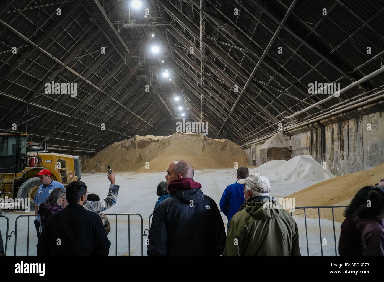 Das Innere der Redpath Zuckerfabrik mit großen Häufchen Rohzucker und Besuchern. Industrielle Produktionsstätte in Toronto, Kanada. Stockfoto