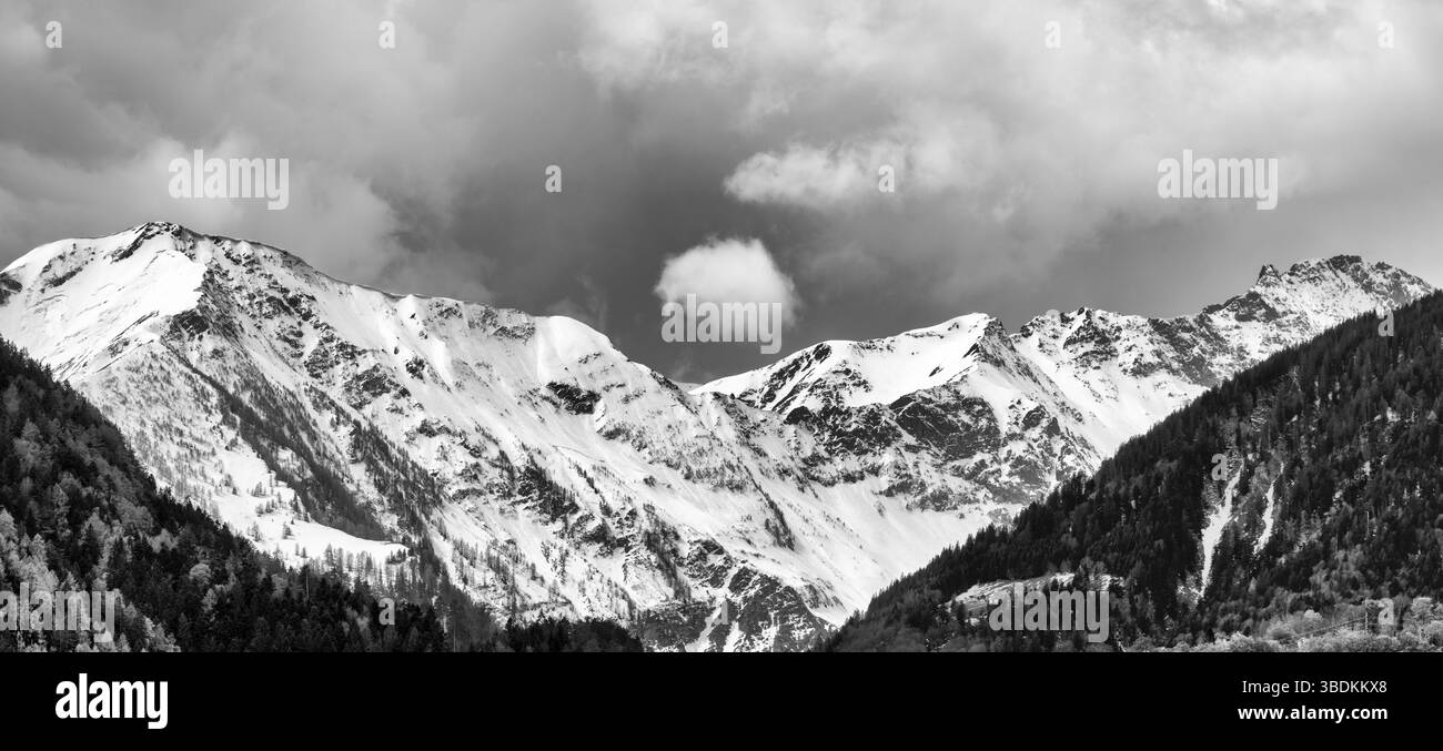 Schwarze und weiße panorama Bergwelt mit schneebedeckten Gipfeln und ausdrucksstarke cloudscape im späten Frühjahr Stockfoto