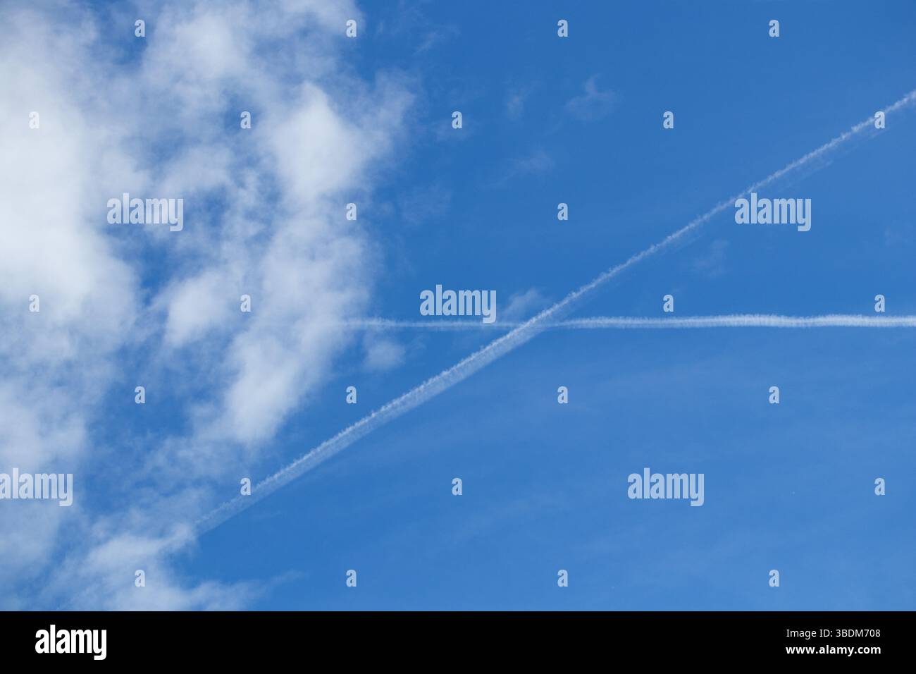 Heller, sonniger Tag mit langen, weißen Kondensationspfaden, die von Jets hinterlassen werden, die sich perfekt durch die weite Weite ziehen. Stockfoto Heller, sonniger Tag mit langen, weißen Kondensationspfaden, die von Jets hinterlassen werden, die sich perfekt durch die weite Weite ziehen. Stockfoto