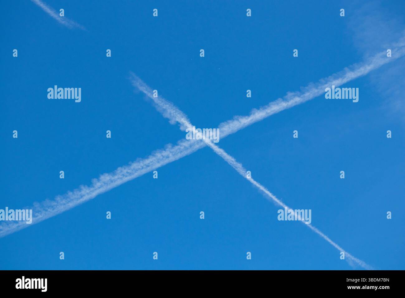 Heller, sonniger Tag mit langen, weißen Kondensationspfaden, die von Jets hinterlassen werden, die sich perfekt durch die weite Weite ziehen. Stockfoto Heller, sonniger Tag mit langen, weißen Kondensationspfaden, die von Jets hinterlassen werden, die sich perfekt durch die weite Weite ziehen. Stockfoto